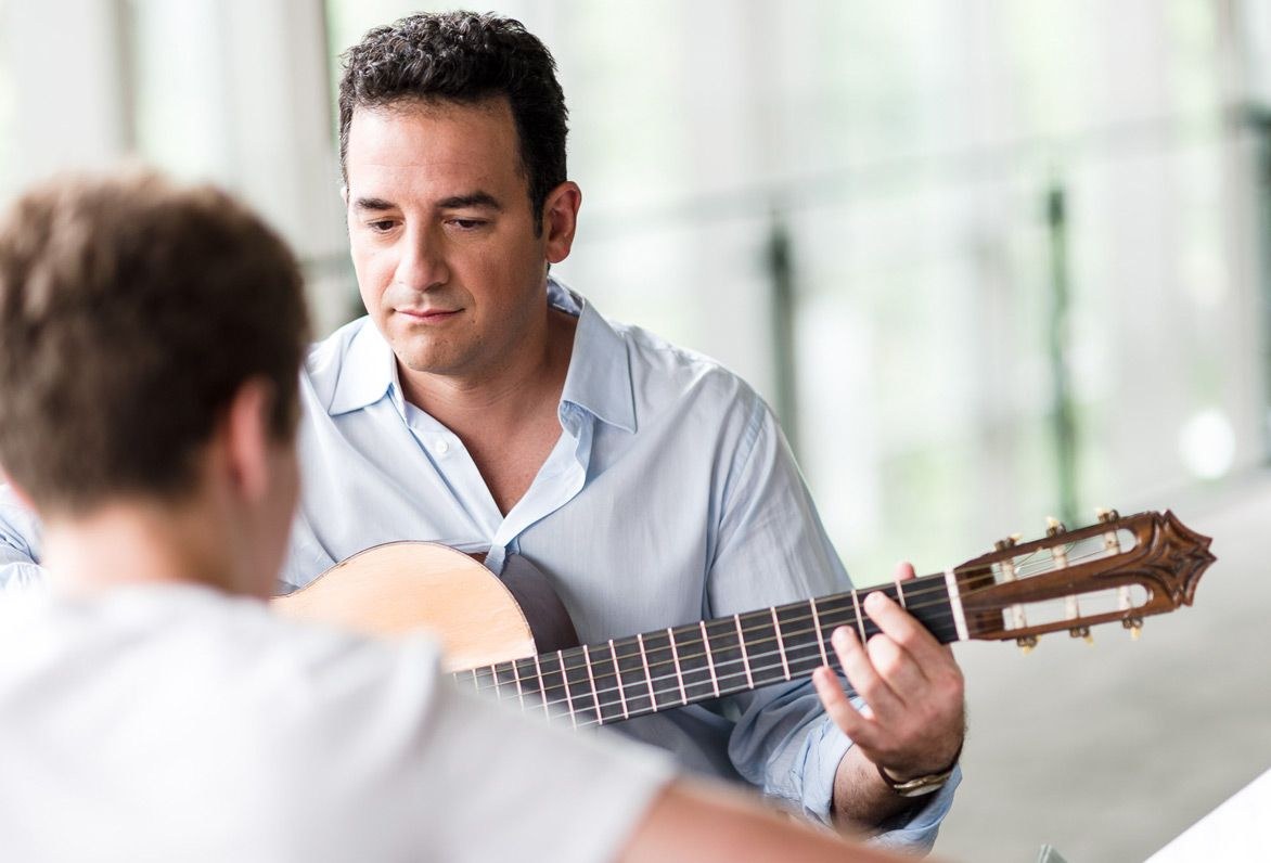 techger teaching the boy to play guitar